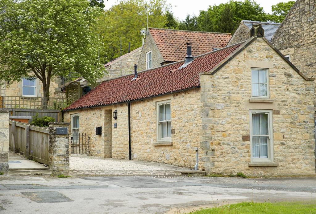 Mason's Cottage في Ampleforth: منزل حجري قديم بسقف احمر