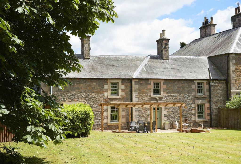 an old stone house with a wooden pergola at Courtyard House in Kelso