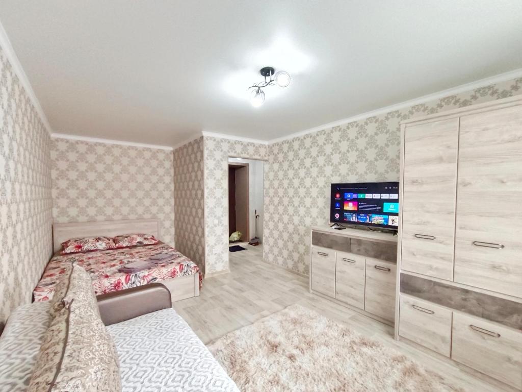 1 dormitorio con 1 cama y TV de pantalla plana en Люксовые апартаменты в Центре г.Семей, en Semey
