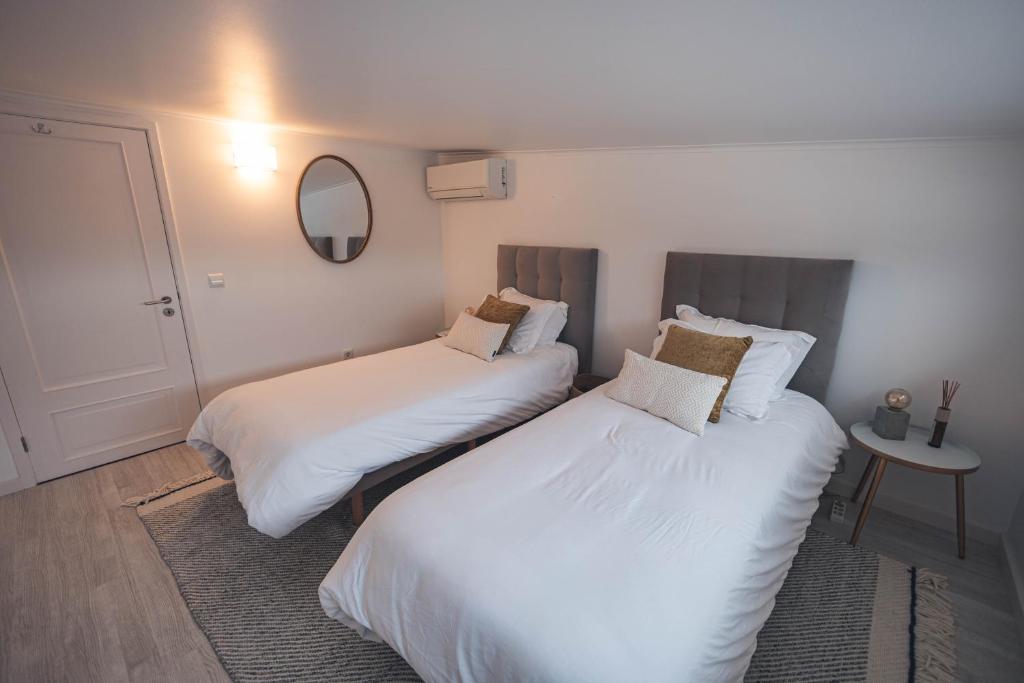 two beds in a small room with a mirror at Ribeira Grande Ocean View Apartment in Ribeira Grande