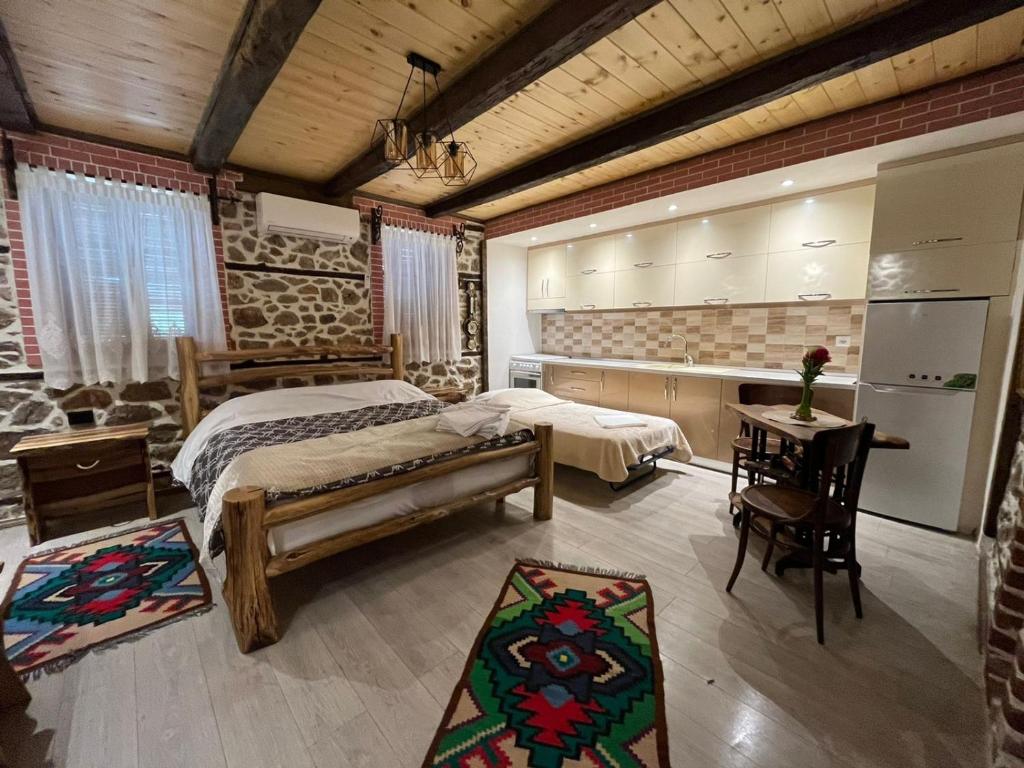 ein Schlafzimmer mit einem Bett und einem Tisch sowie eine Küche in der Unterkunft Vila Gregor in Tushemisht