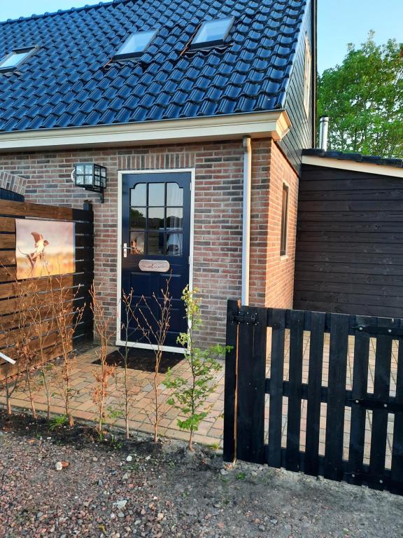 una casa con una puerta azul y una valla en B&B De Boeren Zwaluw, en Slochteren