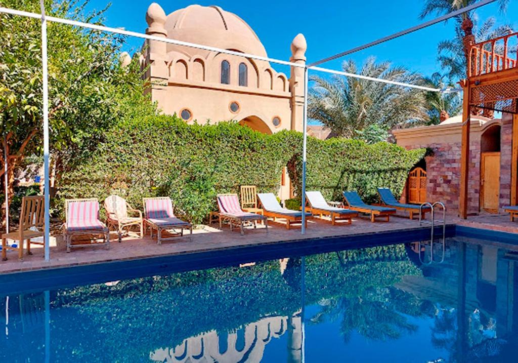 a group of chairs sitting next to a swimming pool at Embrace Hotel in Luxor