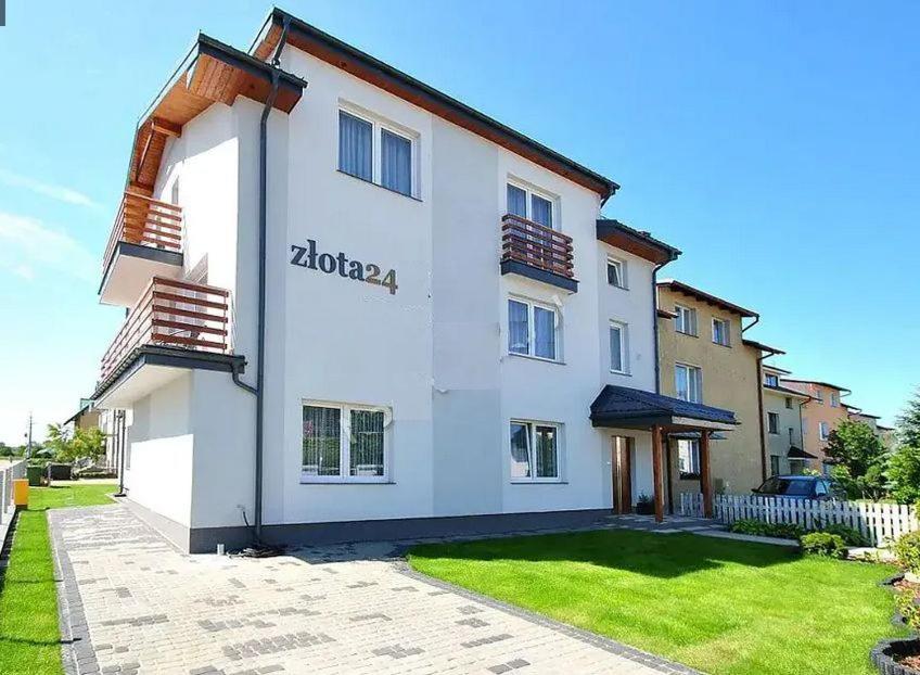 a white building with a sign on the side of it at Złota 24 in Karwia