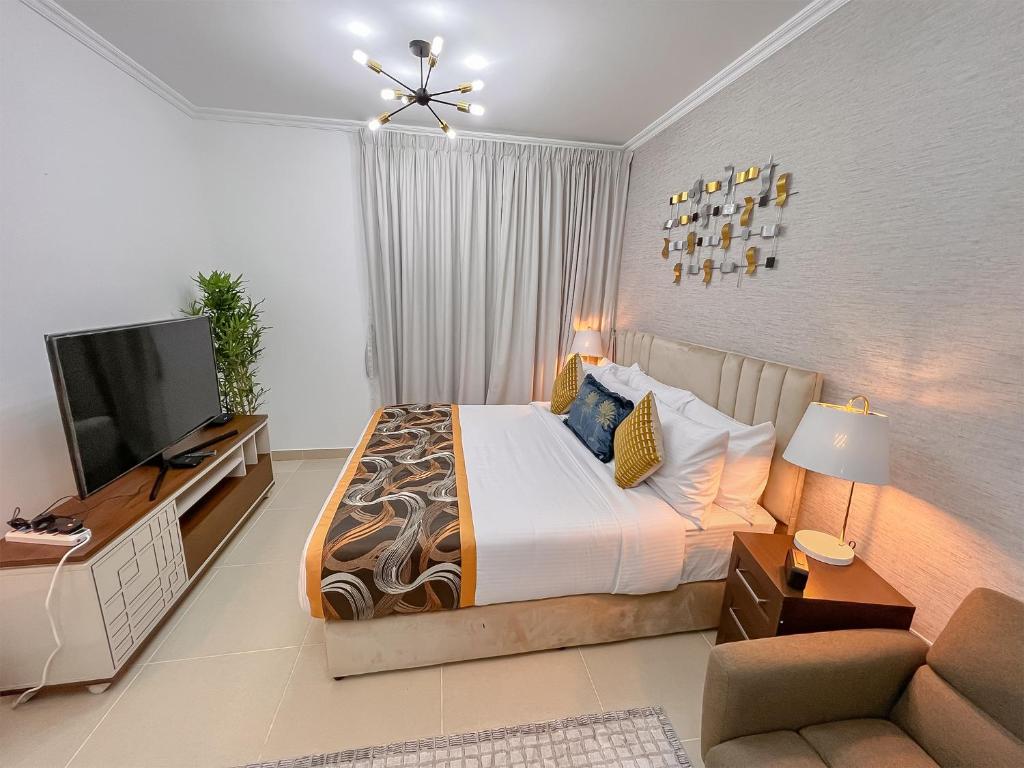a bedroom with a large bed and a television at Cosmos Living Luxurious Studio Near Metro in Dubai