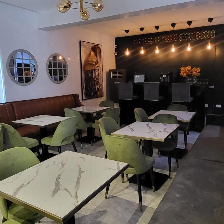 un comedor con mesas y sillas verdes en melbrookeparkhotel en Lagos