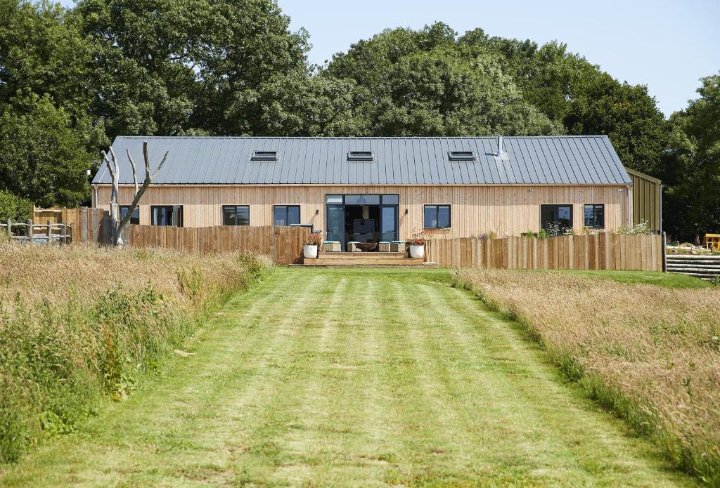 a barn with a dirt road in front of it at Bokes Barn in Hawkhurst