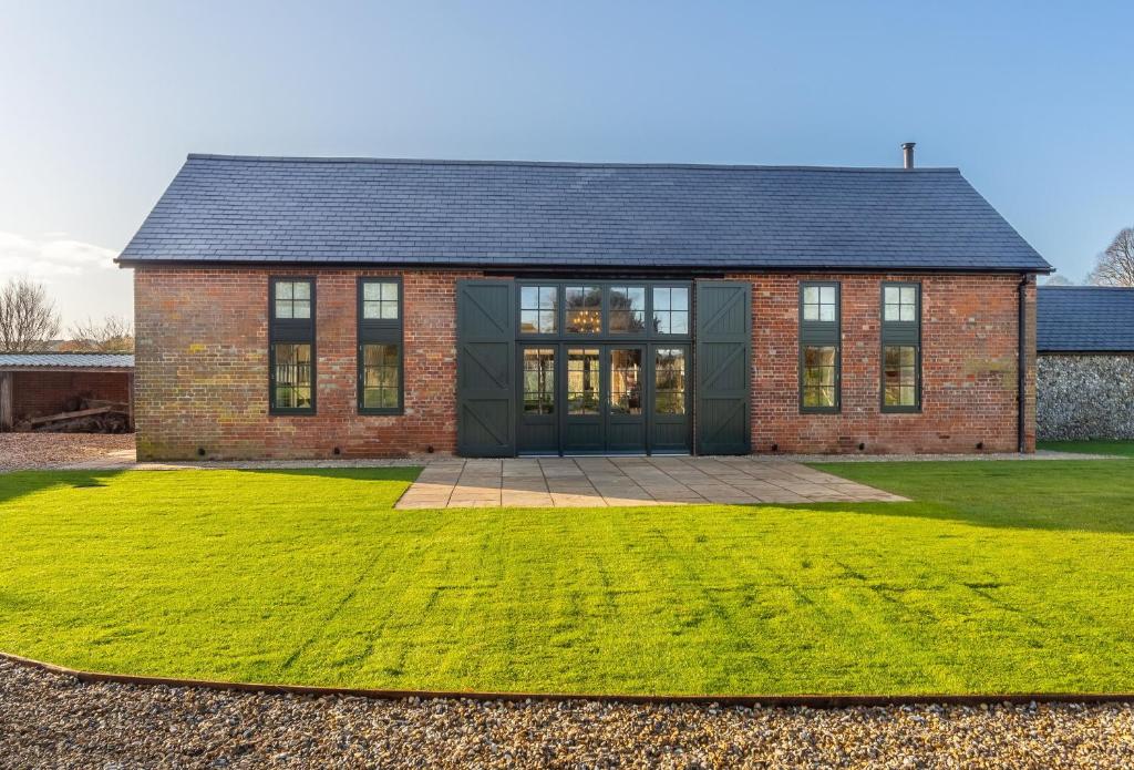 a brick house with a green lawn in front of it at Bodney Lodge in Bodney