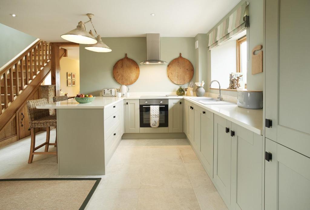 a large kitchen with white cabinets and a staircase at The Stone Barn in Downton