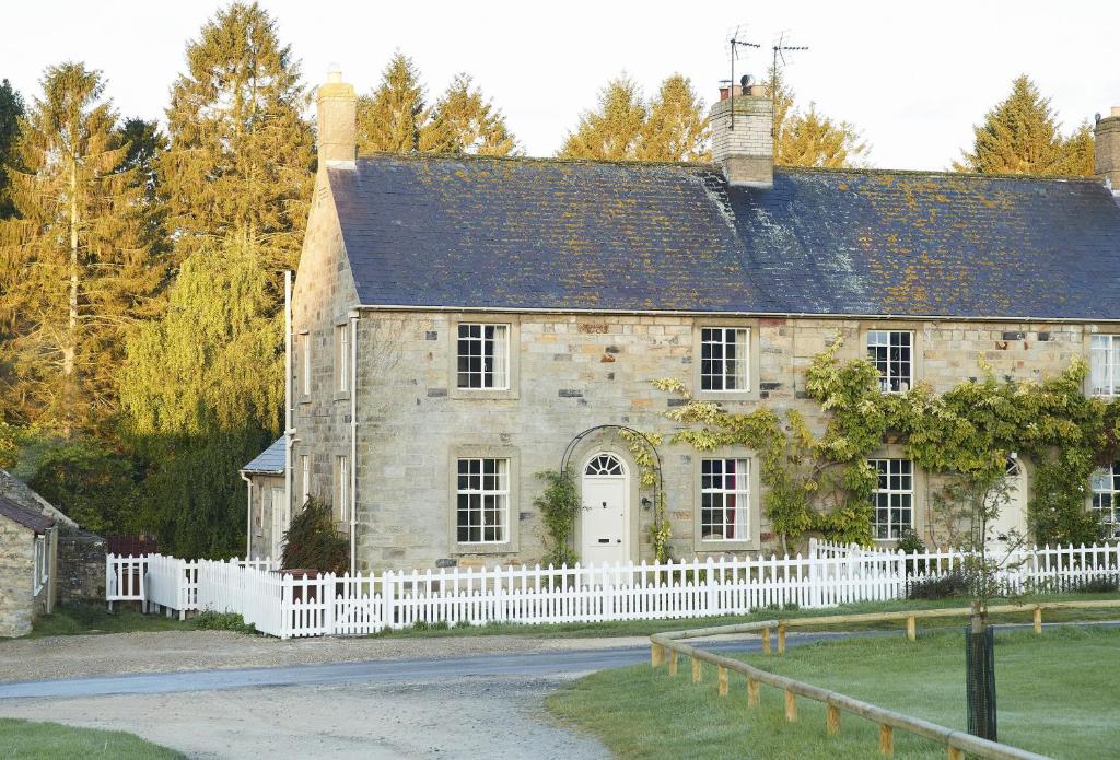 an old stone house with a white fence at The Green in Coneysthorpe