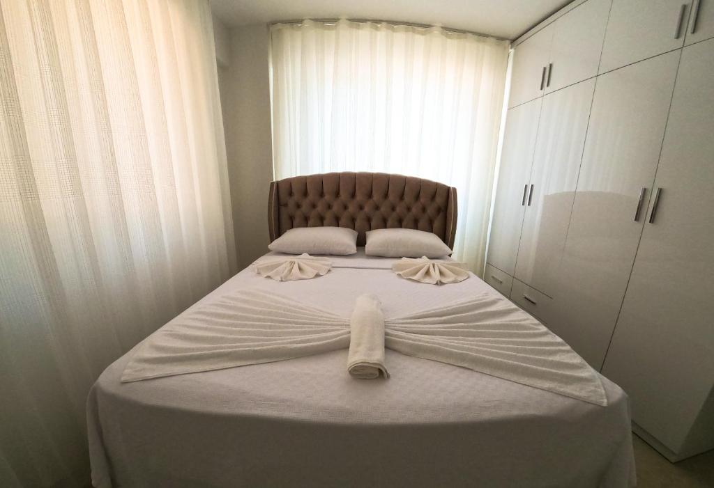 a bedroom with a bed with white sheets and a chair at Doğa Apart in Ortaca