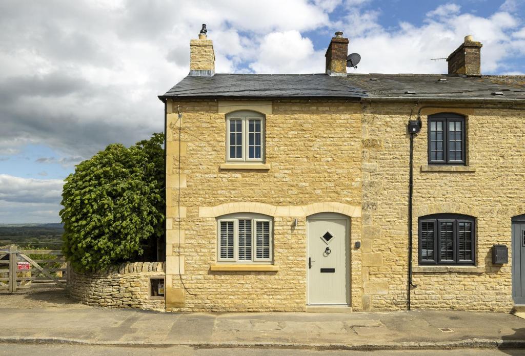 an old brick house with a white door at The Gap in Blockley