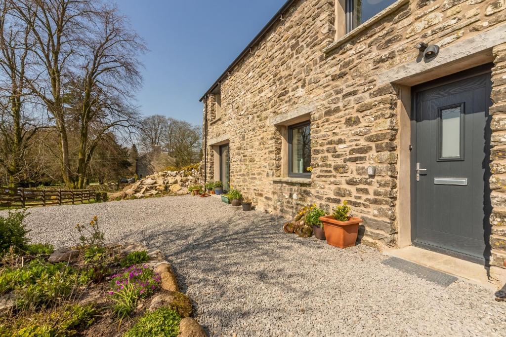 a stone house with a door and a gravel driveway at Linden Barn in Orton