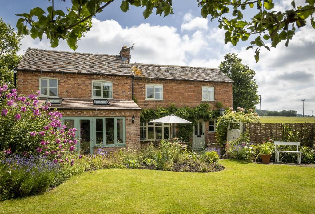 a brick house with a garden in front of it at Southcroft Cottage in Bredon