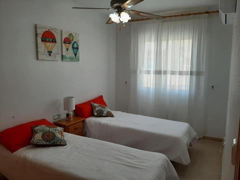 1 dormitorio con 2 camas y ventana en Vistamar II, en Cabo Roig