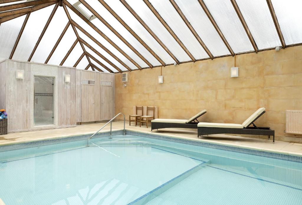 a swimming pool in a building with a roof at Cats Abbey Cottage in Northleach