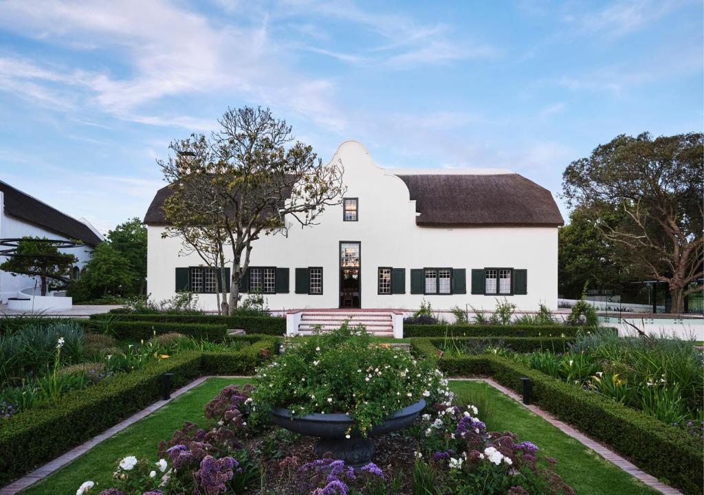 a white house with a garden in front of it at The Homestead at Hazendal, in Stellenbosch Winelands by NEWMARK in Stellenbosch