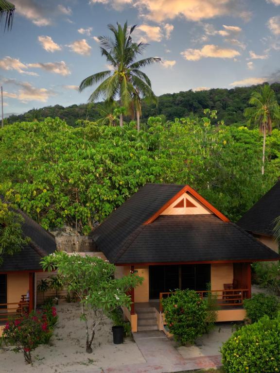a house in front of a hill with trees at Cruiser Island By Swiss-Belhotel in Ko Lone