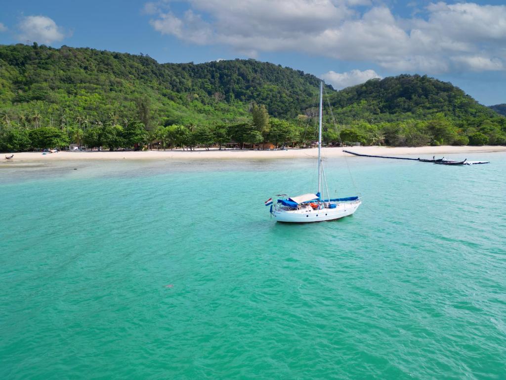 a sailboat in the water next to a beach at Cruiser Island By Swiss-Belhotel in Ko Lone