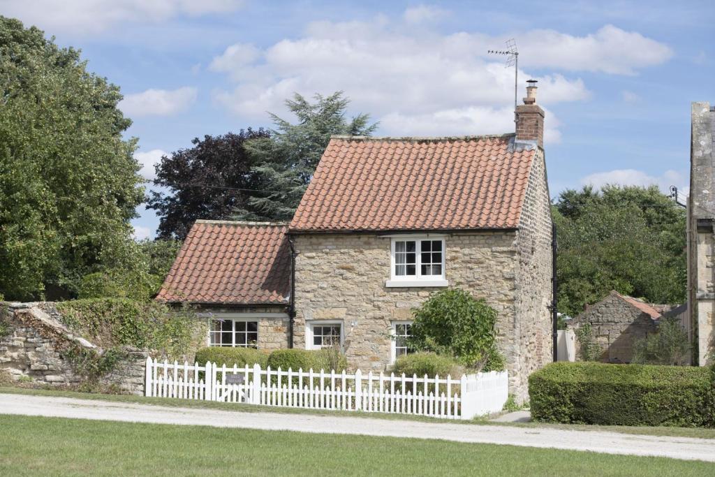 an old stone house with a white fence at Beau Repaire in Coneysthorpe