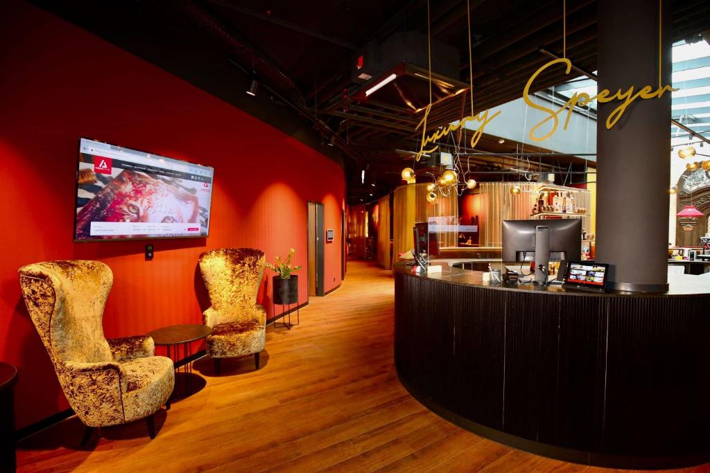 un bar con 2 sillas y TV en la pared en Amedia Plaza Speyer, Trademark Collection by Wyndham, en Speyer