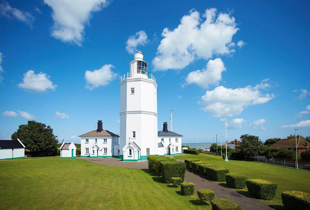 a white lighthouse with bushes in front of a building at Khina Cottage in Kingsgate