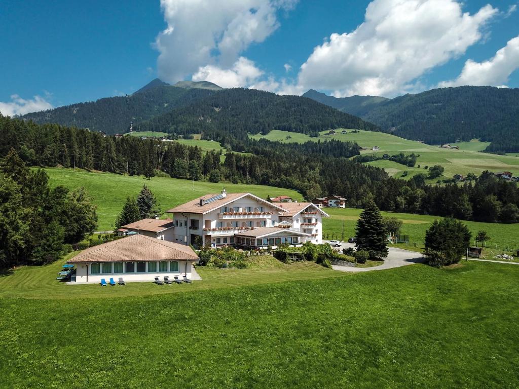 a house in a green field with mountains in the background at Hotel Moserhof in Terento