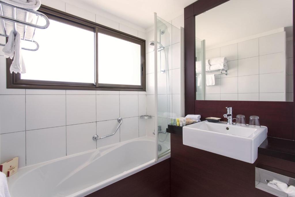 bagno con vasca, lavandino e finestra di Ramada Hotel & Suites by Wyndham Noumea a Noumea