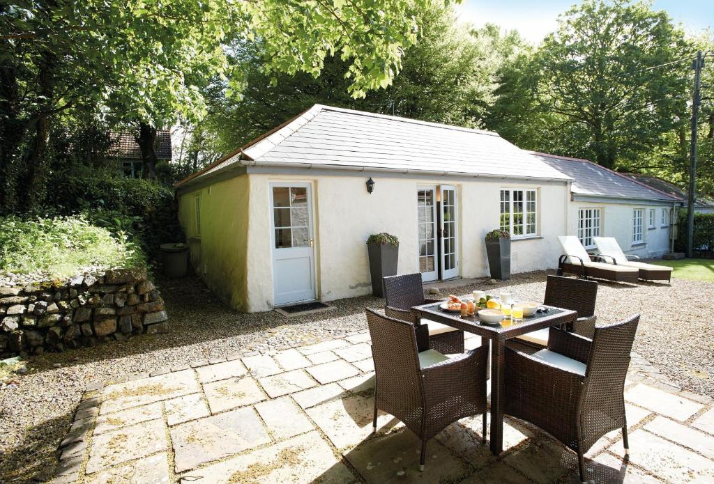 a patio with a table and chairs and a shed at Spring Water Barn in Helston