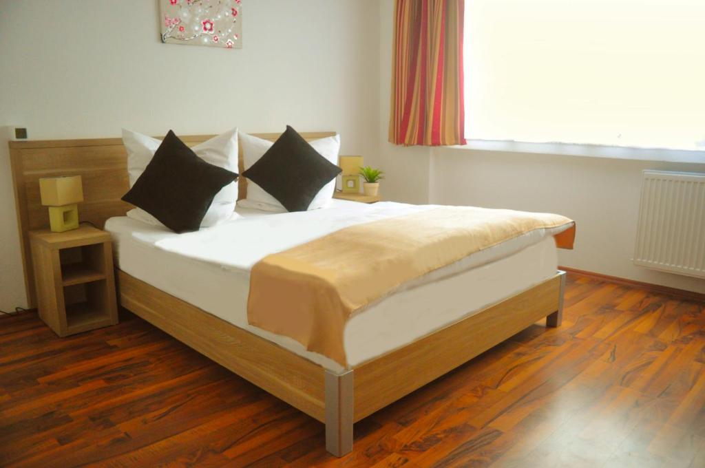 een slaapkamer met een groot bed, houten vloeren en een raam bij Hotel Platinium in Aken