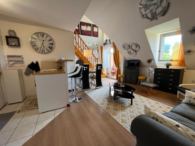 un salon avec un canapé et une horloge au mur dans l'établissement L'Ancre Rouge Deauville, à Deauville