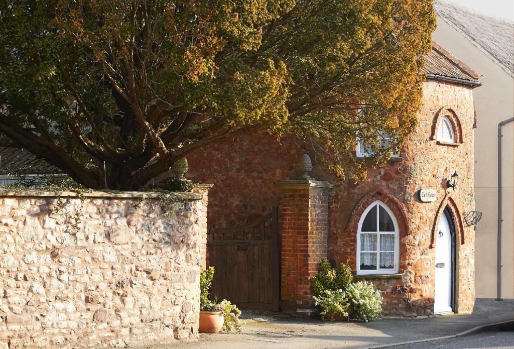 a brick building with a door and a tree at Toll House in Nether Stowey