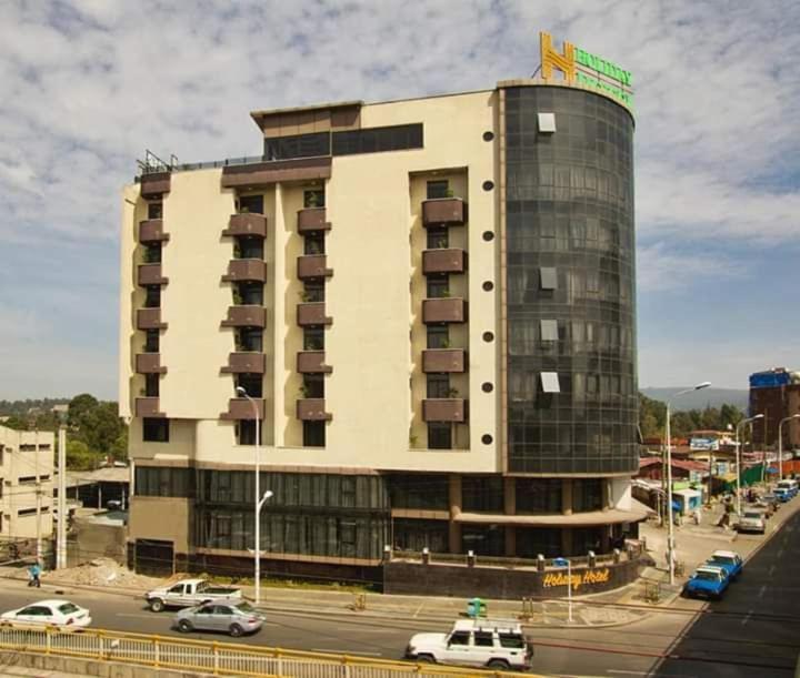 un grande edificio con macchine parcheggiate di fronte di Holiday Hotel Addis Ababa ad Addis Abeba