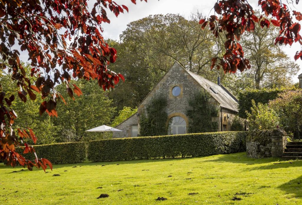 una casa con un seto delante de un patio en Coach House Hawling en Hawling