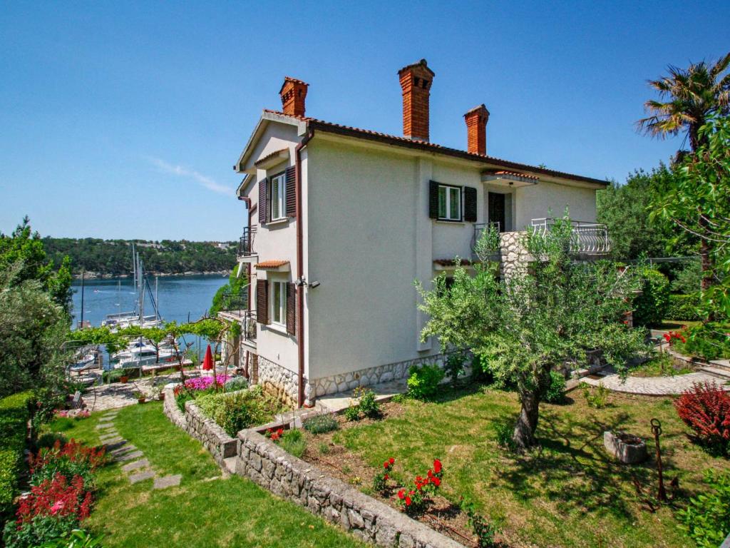 a house with a garden in front of a body of water at Apartment Marija-1 by Interhome in Omišalj