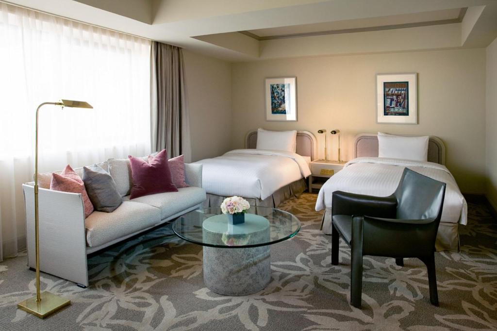 a hotel room with two beds and a couch at Hotel Nikko Fukuoka in Fukuoka