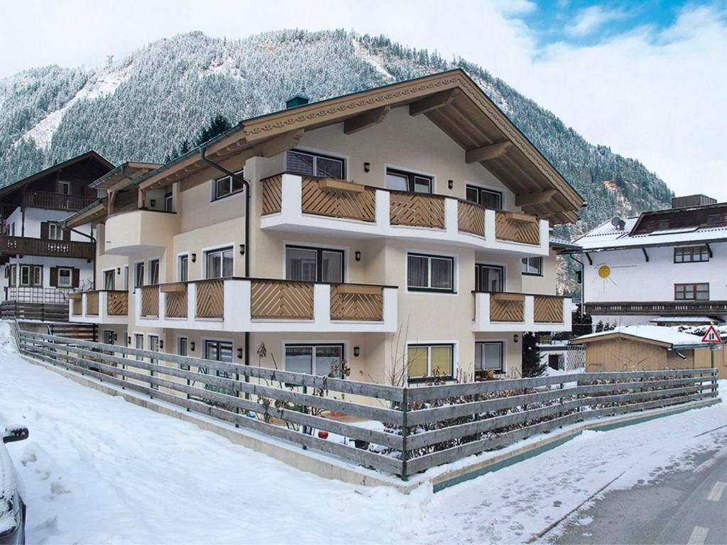 a building in the snow with mountains in the background at Apartment Rosa-8 by Interhome in Mayrhofen