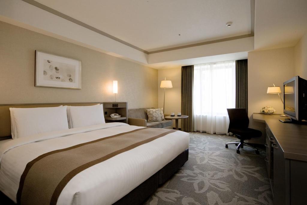 a hotel room with a large bed and a desk at Hotel Nikko Fukuoka in Fukuoka