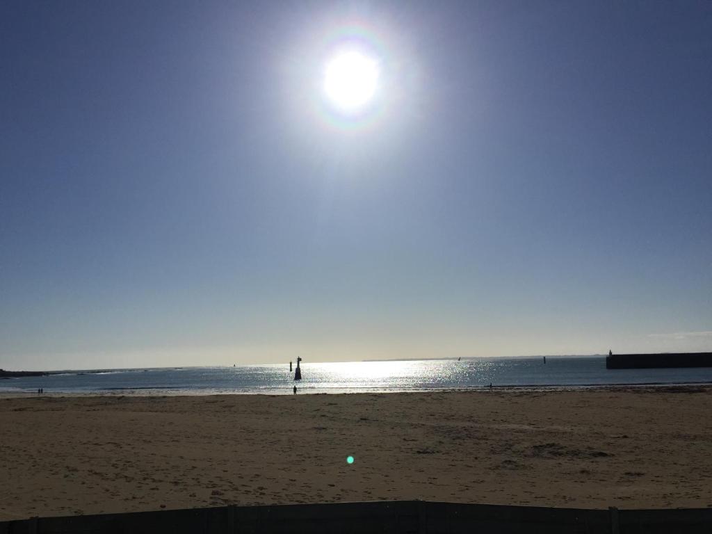 a person standing on a beach with the sun in the water at A deux pas de la grande plage in Quiberon