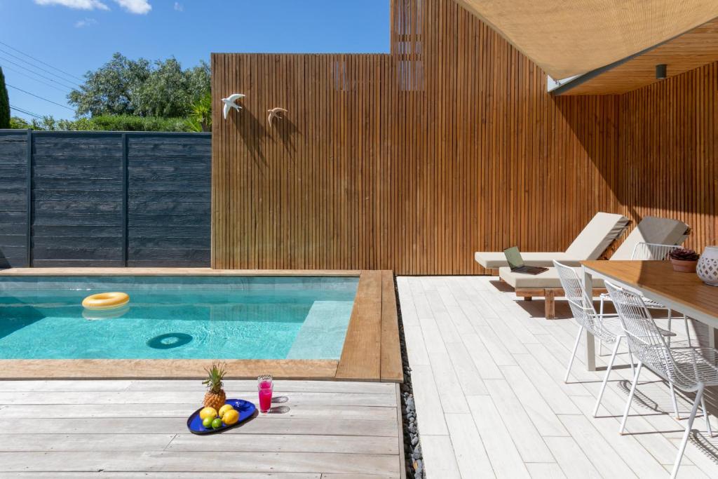 - une piscine avec une table et des chaises à côté dans l'établissement Villas les Capucines, à Sète