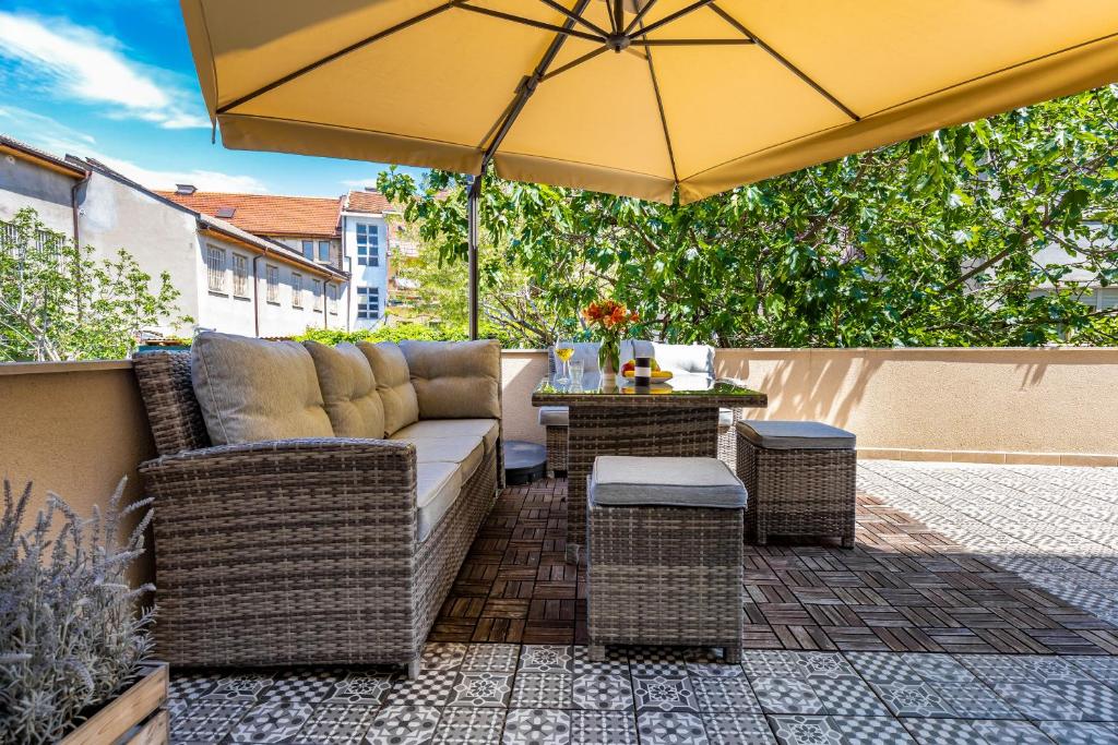eine Terrasse mit einem Sofa und einem Sonnenschirm in der Unterkunft Apartment Obelix / Kapana / Center Private Parking in Plowdiw