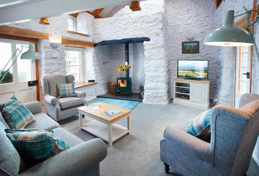 a living room with a stone wall with a fireplace at Rhiwelli in Dinas