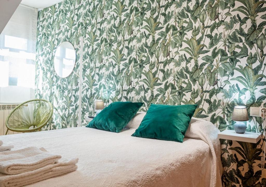 una camera da letto con un letto con cuscini verdi e carta da parati di Apartamento Irene céntrico con Wifi y parking coche tamaño medio Cangas de Onís a Cangas de Onís