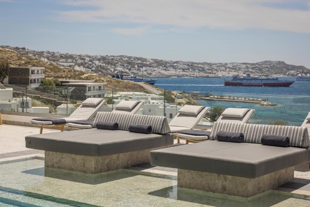 a group of lounge chairs and a view of the water at Grace Mykonos in Agios Stefanos