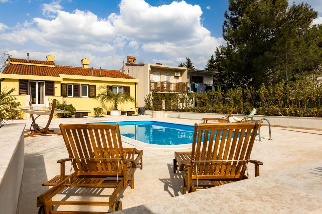 2 sillas y una piscina frente a una casa en Holiday Home PUNAT OASIS with breathtaking Sunset & Sea View, en Punat