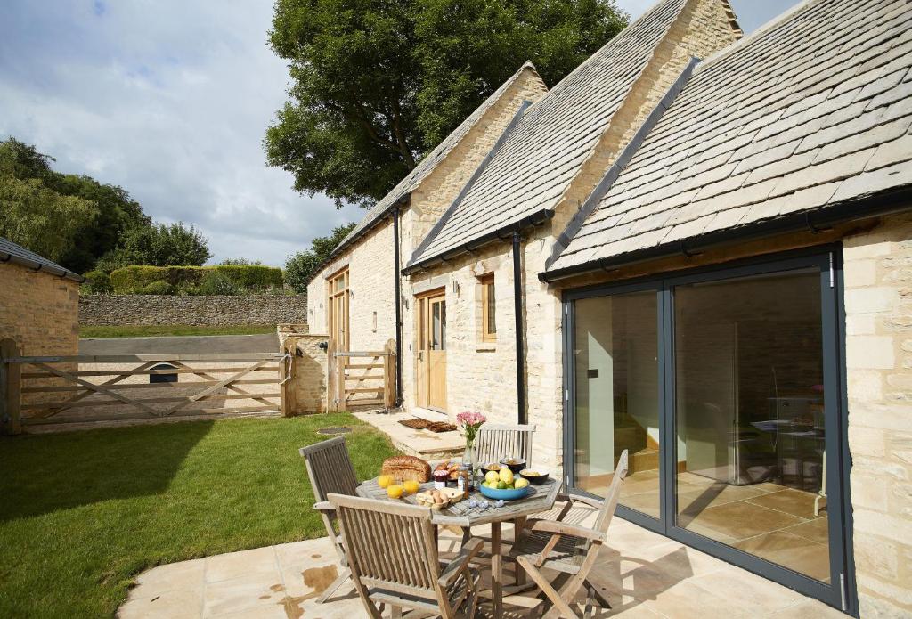 a patio with a table and chairs in front of a building at Rosebank Barn in Bibury