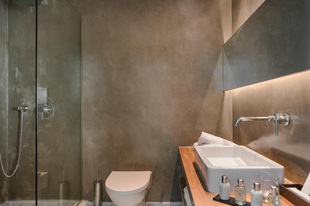 a bathroom with a toilet and a sink and a shower at Grace Mykonos in Agios Stefanos