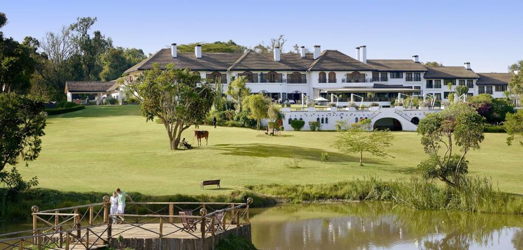 une grande maison sur un parcours de golf à côté d'un étang dans l'établissement Fairmont Mount Kenya Safari Club, à Nanyuki