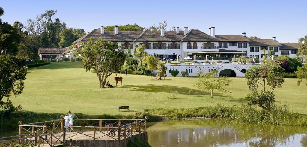 una casa grande en un campo de golf junto a un estanque en Fairmont Mount Kenya Safari Club, en Nanyuki