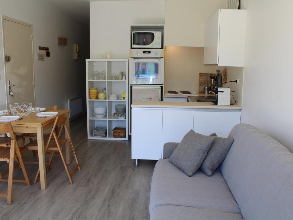 un salon avec un canapé et une table et une cuisine dans l'établissement Appartement T2 avec terrasse, parking privé, proche plage et commerces - FR-1-229C-9, à Port-la-Nouvelle